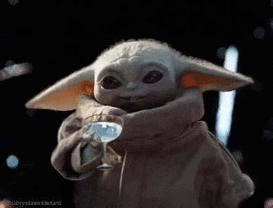 the child yoda is holding something in his hands and wearing a star wars outfit