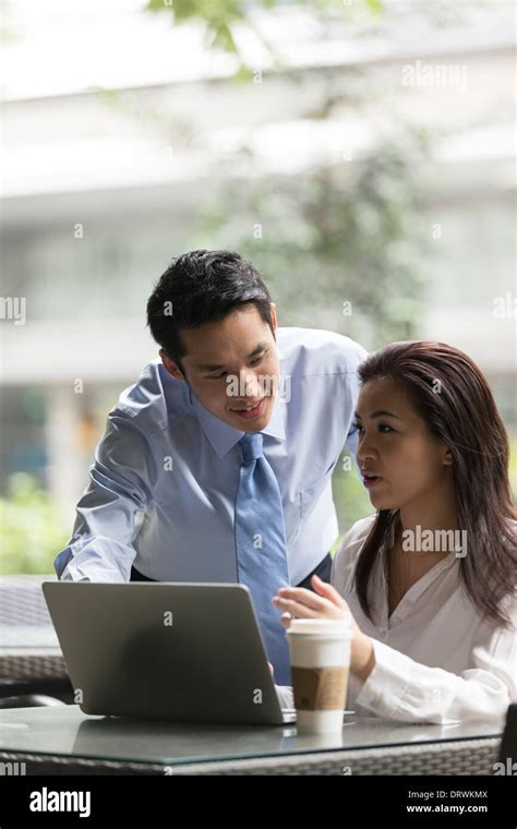 Chinese business Man and woman working together on a laptop outdoors in modern city Stock Photo ...