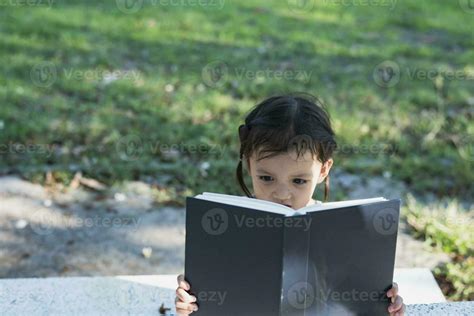 Asian girl sitting on a bench and reading a book in the park. 23744881 ...