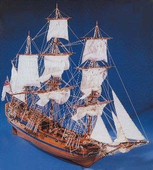 a wooden model ship with white sails