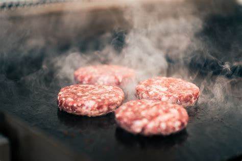 Premium Photo | Raw meat burgers on a grill.