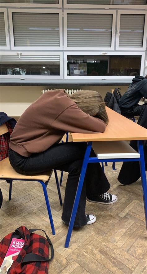 two people sleeping on desks in a classroom