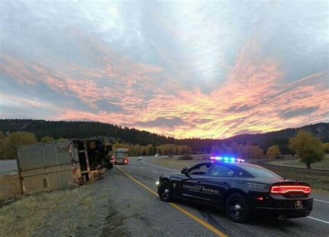 a police car is parked on the side of the road near a semi - truck