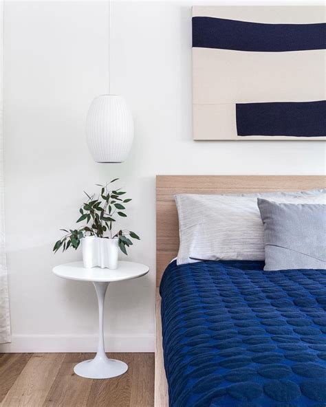 a bed with blue sheets and pillows next to a white table