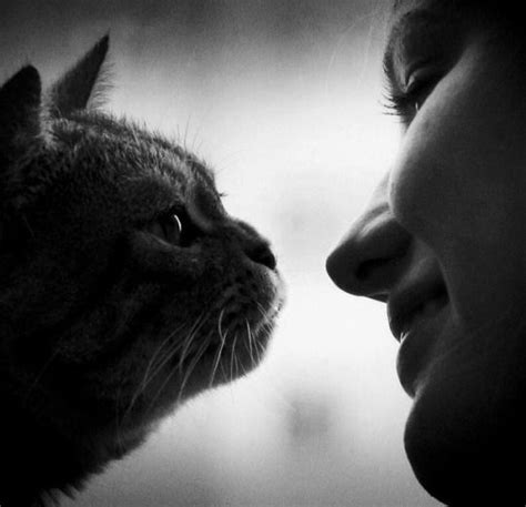 a black and white photo of a woman kissing a cat's face with her eyes closed