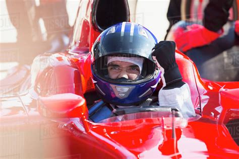 Formula one race car driver in helmet gesturing, celebrating victory - Stock Photo - Dissolve