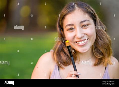 Petite Young Asian Woman Student Holding a Paint Brush with Yellow Acrylic Paint Stock Photo - Alamy