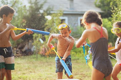 Children Playing With Water Guns In The Yard. by Dejan Ristovski