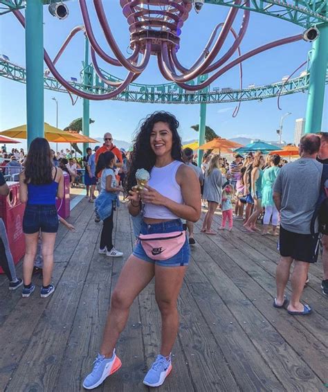 a woman holding an ice cream cone standing on a wooden deck with people ...