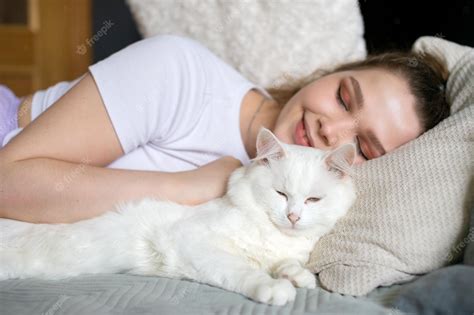 Premium Photo | Cute girl sleeping on a bed next to a white cat