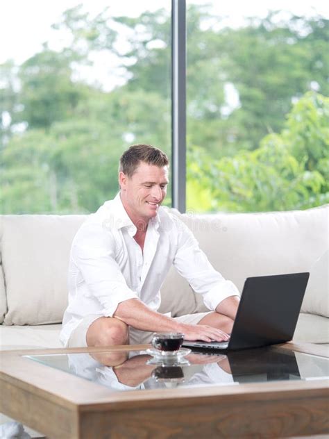 Man Sitting on Sofa with Laptop in Summer House Environment Stock Photo ...