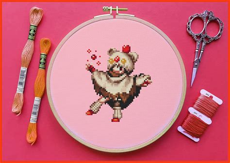 a cross - stitch pattern with scissors and thread next to it on a pink background