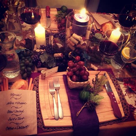 a place setting with candles, wine glasses and fruit on the table in front of it