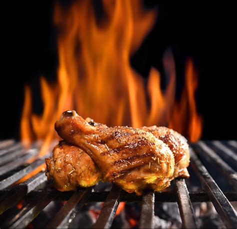 Premium Photo | Grilled chicken legs on the flaming grill