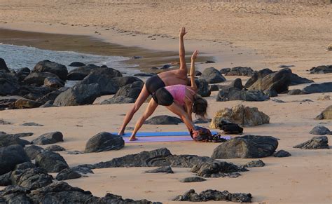 Fit Couple Practicing Yoga At The Beach