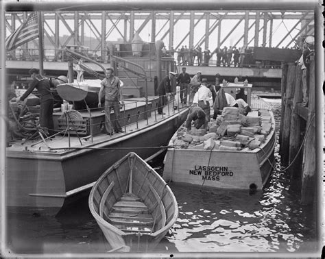 A photograph of officials appraising and seizing illegal cargo from captured rum runners, 1932 ...