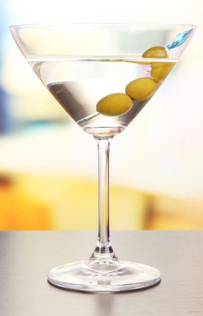 Premium Photo | Martini with green olives on table in bar