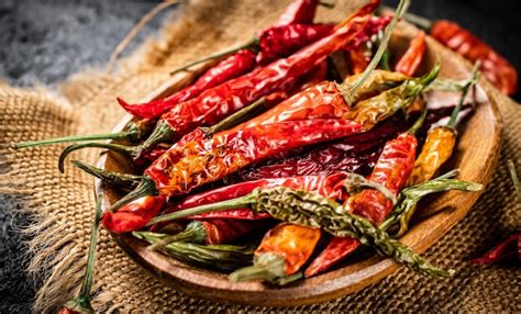 Premium Photo | Pods of dried chili peppers in a wooden plate on a napkin