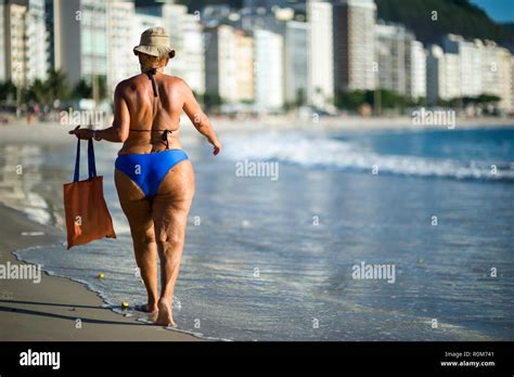 Bright scenic morning view of Copacabana Beach with woman walking along the shore in Rio de ...