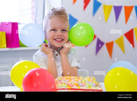 Excited Birthday boy with colorful balloons near birthday rainbow cake. Festivel background ...