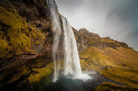 Premium Photo | A waterfall in iceland with a yellow and green landscape.