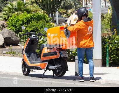 Just Eat courier delivery rider in orange uniform and Just Eat Scooter ...