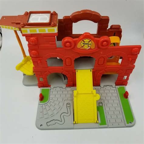 a toy fire station playset on a white surface