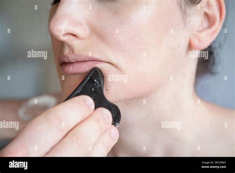 Young Caucasian woman getting facial treatment. Therapist doing skin scrape technique. Chinese ...