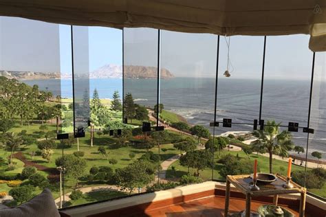 a room with large windows looking out at the ocean and golf course in the distance