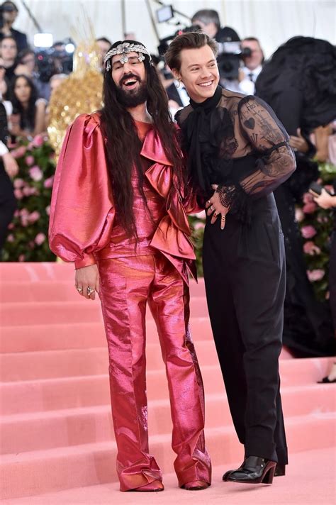 two people standing next to each other on a pink carpet with cameras in ...