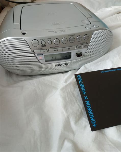 the radio is sitting on top of the bed next to an electronic book and remote control