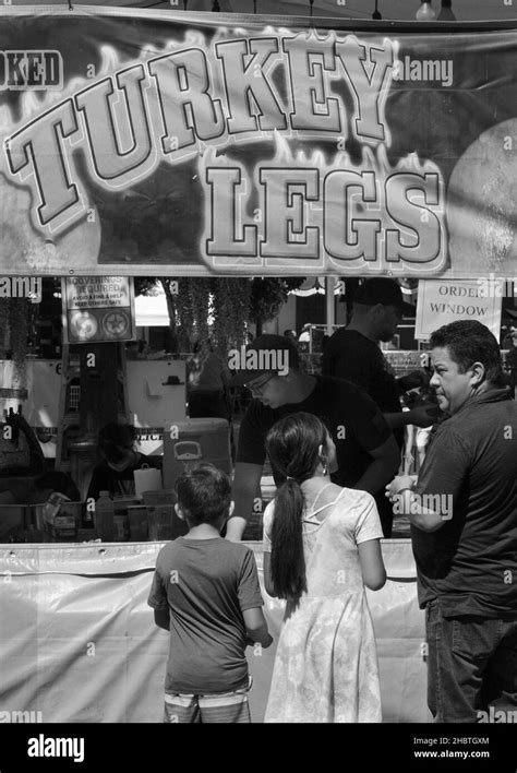 A father buys smoked turkey legs for lhis two children from a food vendor at an outdoor festival ...