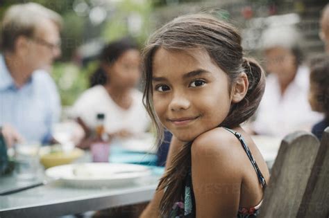 Portrait of smiling girl sitting with family at outdoor dining table stock photo
