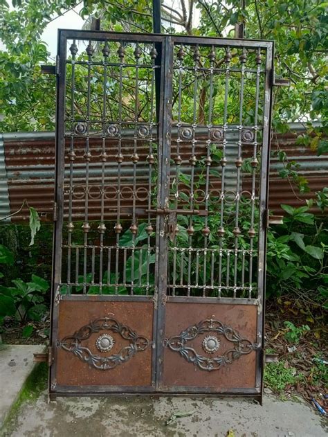 an iron gate is open in front of a wooden bench and some plants on the ...