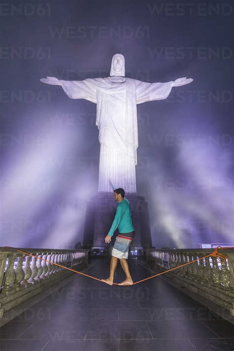 Man slacklining under Christ the Redeemer statue at night at Corcovado ...