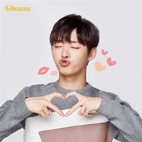 a man making a heart shape with his hands while standing in front of a white background