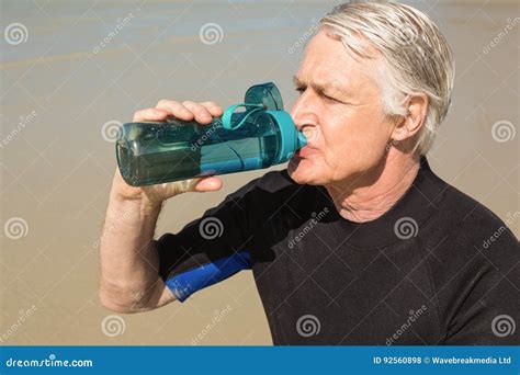 Senior Man Drinking Water while Sitting at Beach Stock Photo - Image of ...