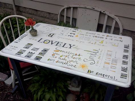 a white table with writing on it and a flower in a vase sitting on top of it