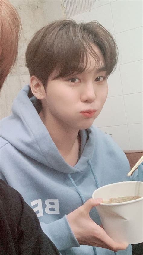 a man in a blue hoodie holding a bowl of cereal and chopsticks