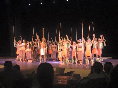 a group of people standing on top of a stage holding up wooden stickes in the air