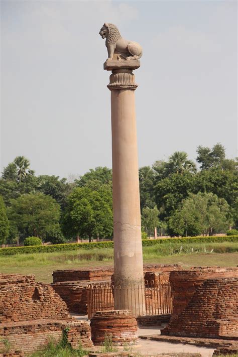 a tall pillar with a lion statue on it's side in the middle of a field