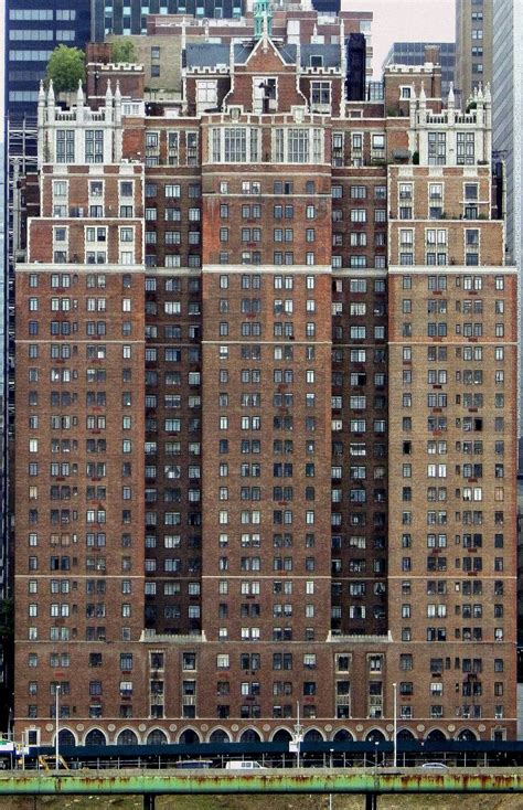 a large building with lots of windows in front of some tall buildings and a bridge