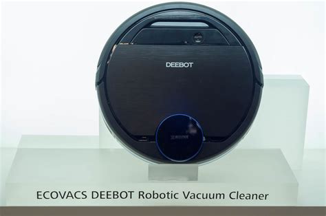 Robotic vacuum cleaner on laminate floor in living room, man presses button to turn on ...