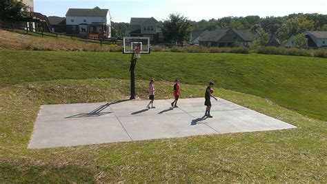 There are three kids playing basketball on their backyard court.