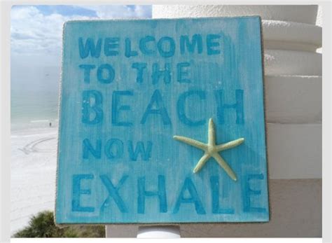 a welcome sign to the beach now exhale