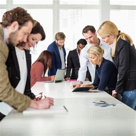 Group of business people working together at desk in office - Stock Photo - Dissolve