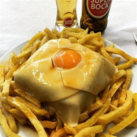 Francesinha - a glorious sandwich of steak, ham, and Portuguese sausage covered in a blanket of ...