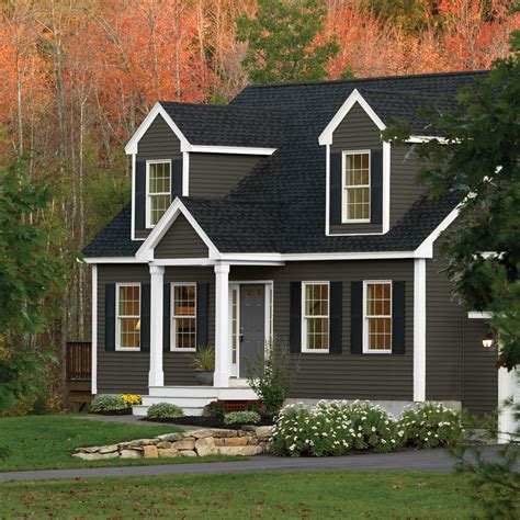 a gray house with white trim and windows in the front yard, surrounded by trees