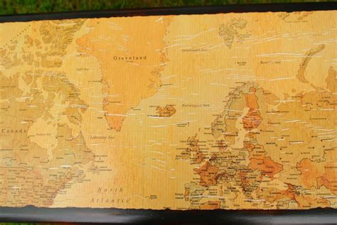 an old world map is displayed on a wooden table with green grass in the background