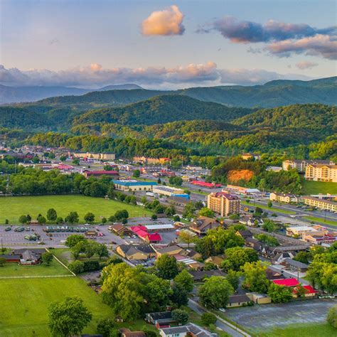 an aerial view of a city with mountains in the background and green ...